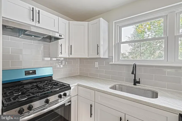 a view of a kitchen with a stove wooden cabinets and windows