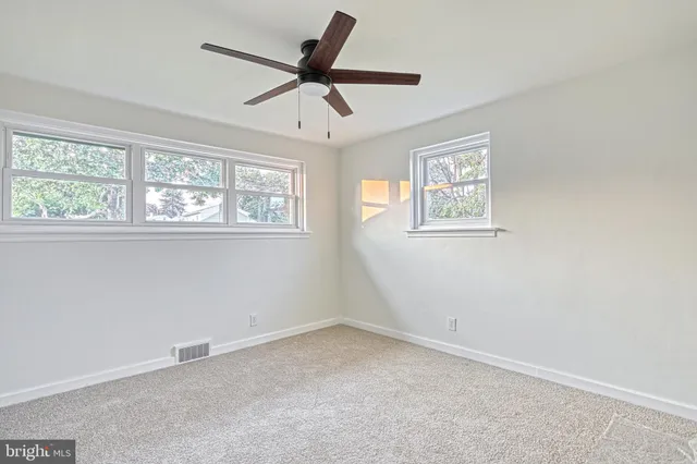 an empty room with windows and fan