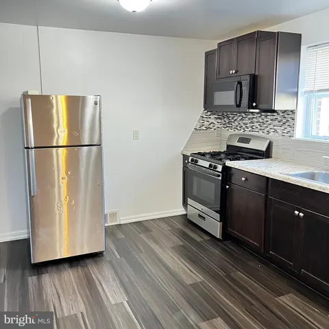 a kitchen with a refrigerator a stove top oven and wooden floors