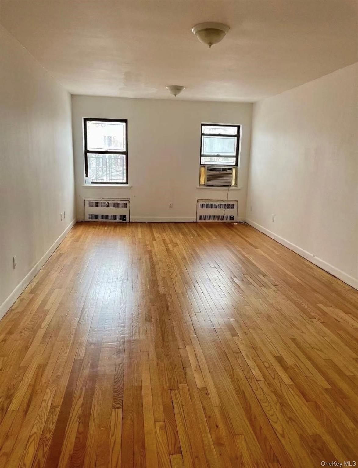 7 Bond Street, Unit 3J Great Neck, NY 11021 - Photo 4 of 10 an empty room with wooden floor and windows