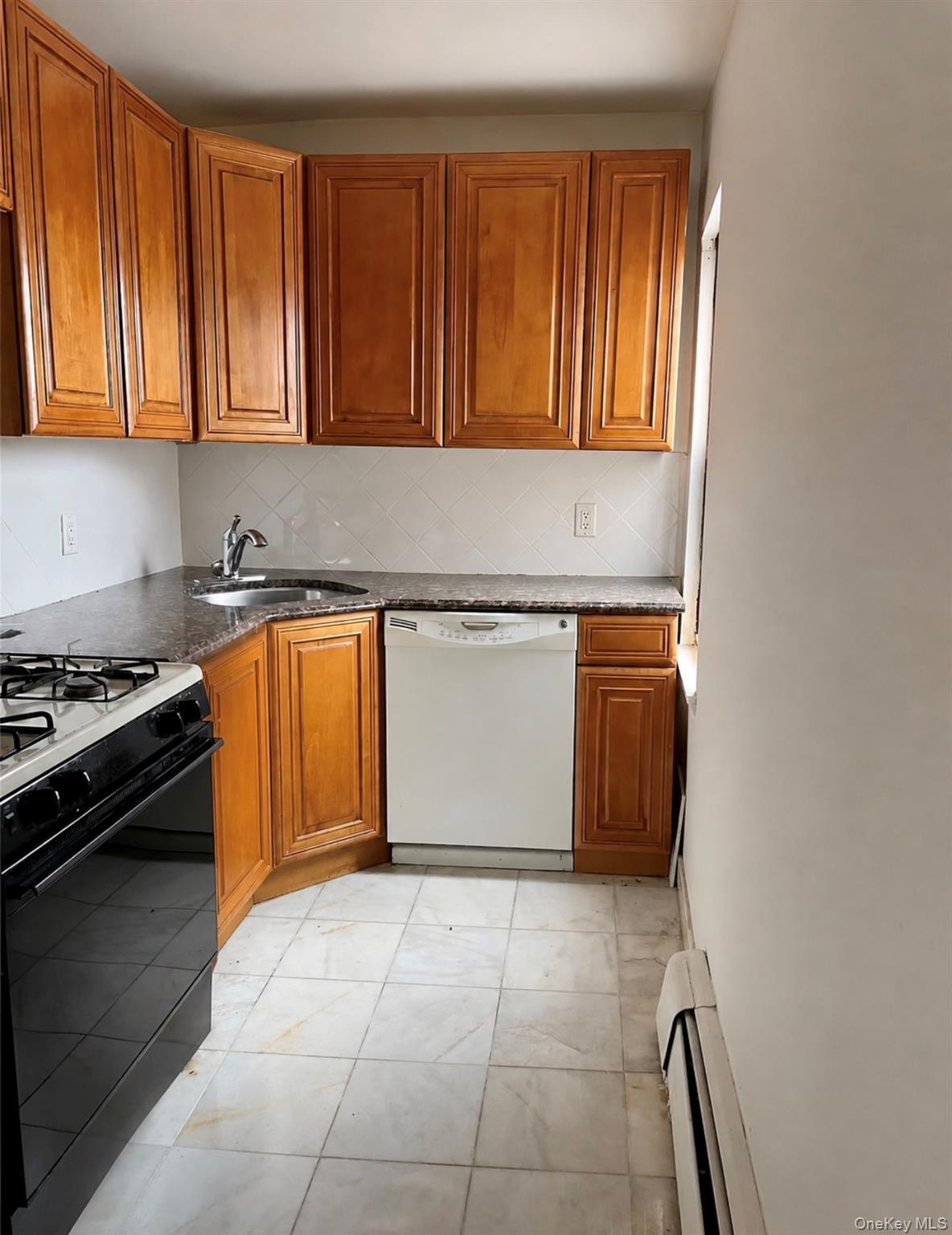 7 Bond Street, Unit 3J Great Neck, NY 11021 - Photo 6 of 10 a kitchen with stainless steel appliances granite countertop a stove a sink and a microwave