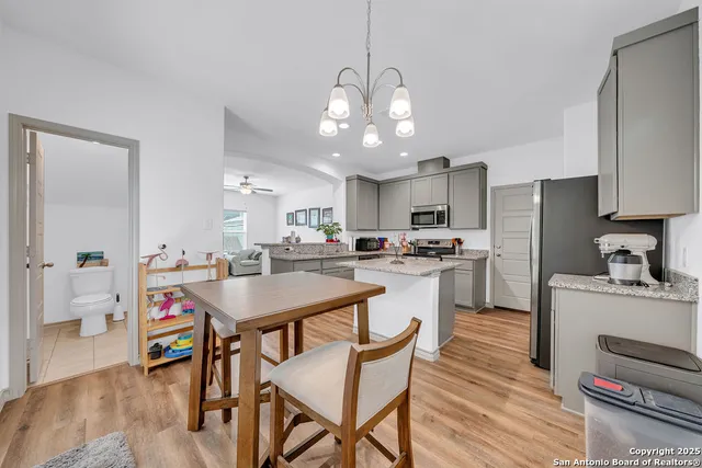 a kitchen with a dining table cabinets appliances and wooden floor