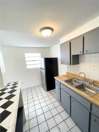 a kitchen with a sink a refrigerator and cabinets