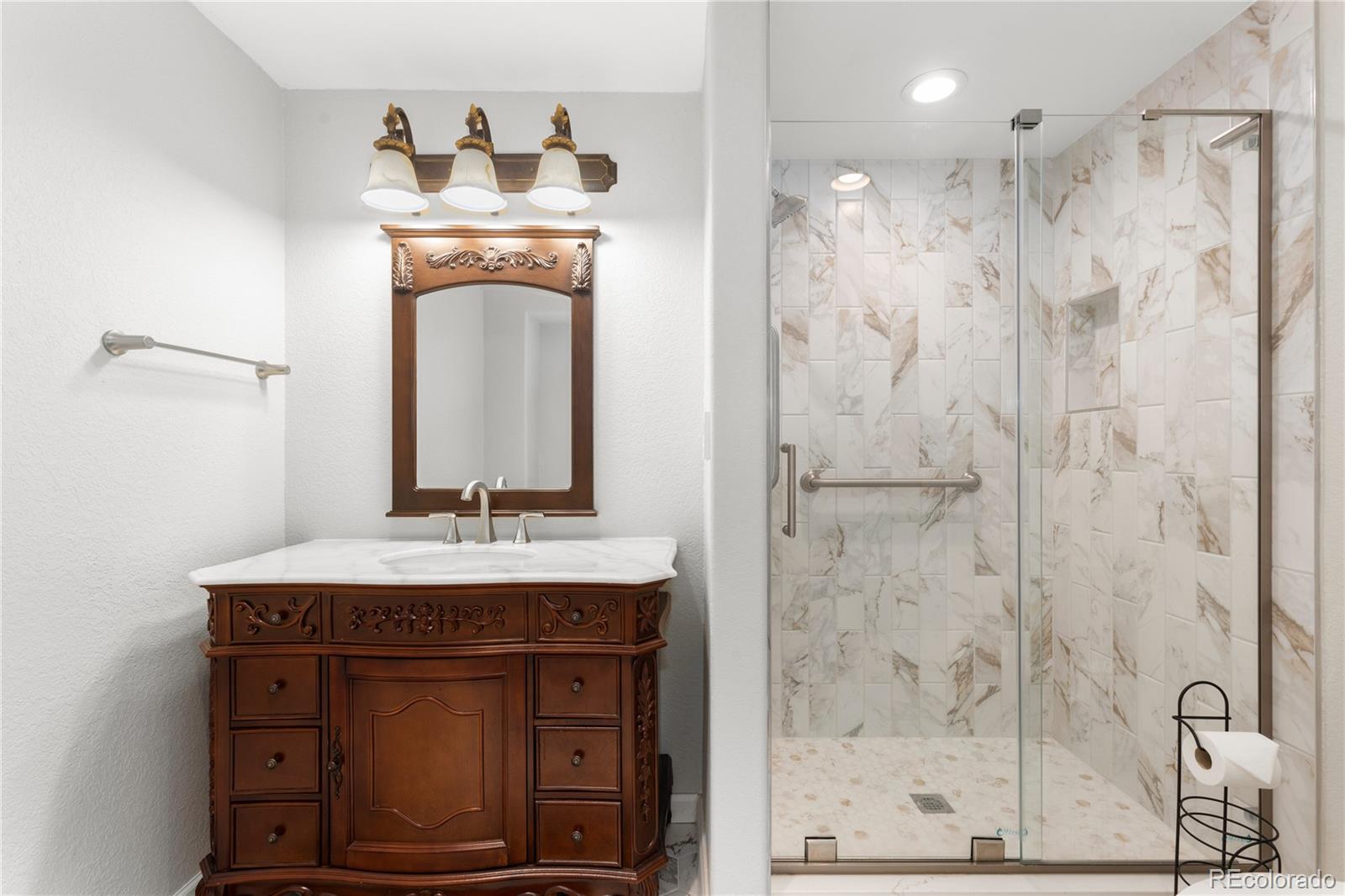 10684 Beas Drive Conifer, CO 80433 - Photo 29 of 38 a bathroom with a granite countertop sink a mirror and shower