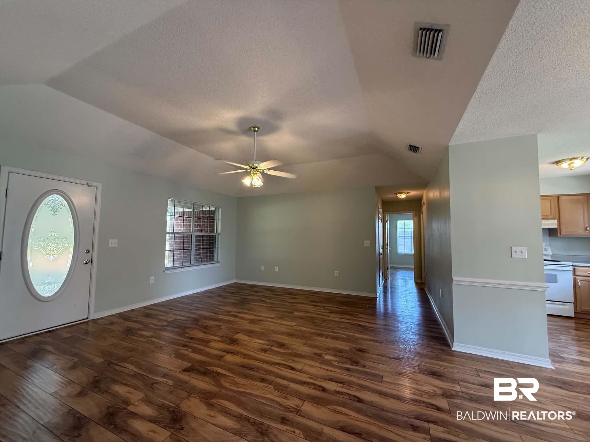 123 Pennbrooke Loop Foley, AL 36535 - Photo 16 of 49 Spacious living area featuring wood-finish flooring, light-toned walls, and a decorative front door with an oval glass insert