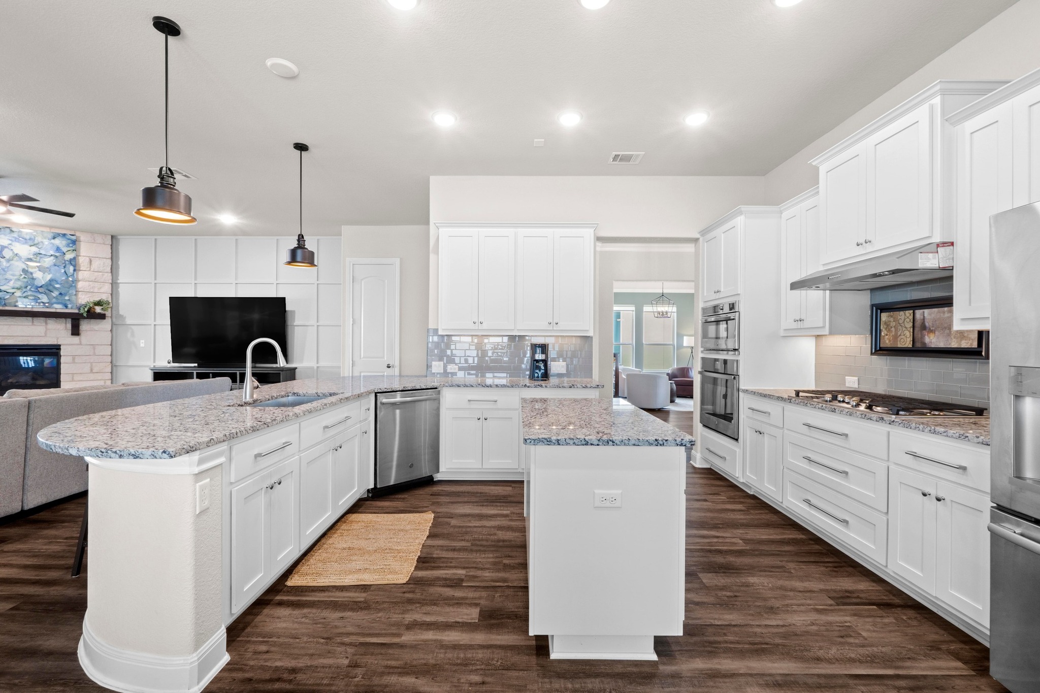 1329 Siena Sunset Road Leander, TX 78641 - Photo 7 of 33 White shaker cabinets, undercabinet lighting, pendant lights, ample recessed lighting, and light granite counters serve this kitchen up as a cooks dream.