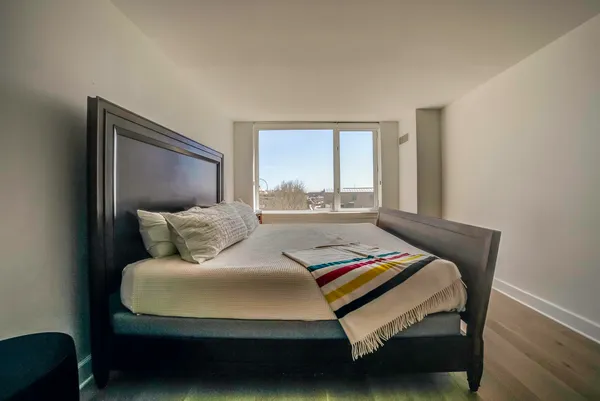 a bedroom with a bed two window and a lamp