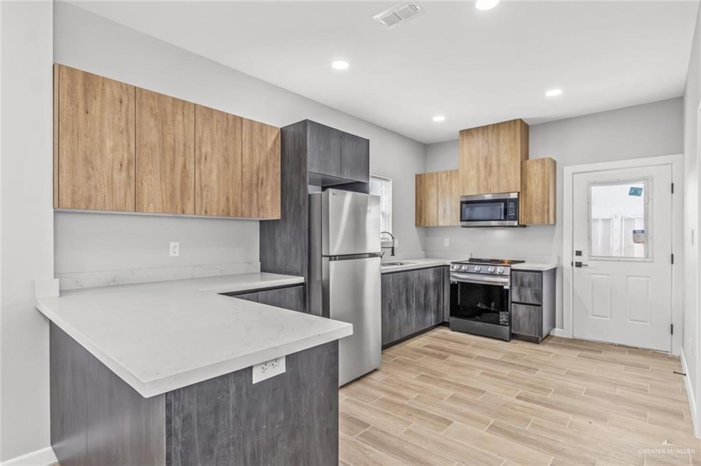103 Yosemite Drive, Unit 3 Mission, TX 78572 - Photo 3 of 9 a kitchen with refrigerator cabinets and wooden floor