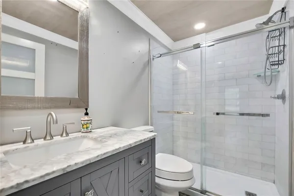 a bathroom with a granite countertop sink a toilet and shower