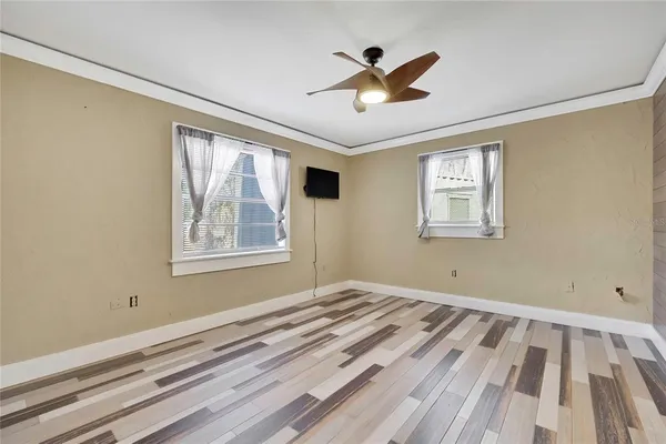 a view of empty room with wooden floor and fan