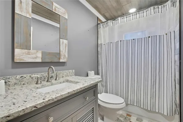 a bathroom with a granite countertop toilet a sink and a mirror
