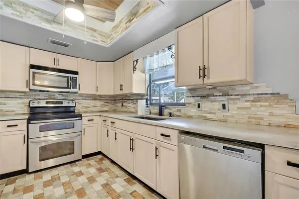 a kitchen with stainless steel appliances granite countertop a sink a stove a microwave oven with white cabinets