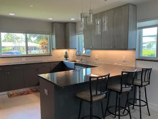 a kitchen with kitchen island granite countertop a table chairs sink and window