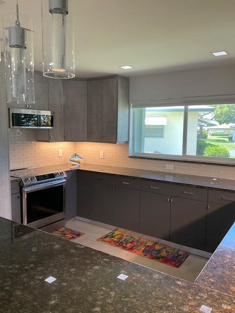224 Cardinal Lane Delray Beach, FL 33445 - Photo 14 of 38 a kitchen with stainless steel appliances kitchen island granite countertop a refrigerator and a stove top oven