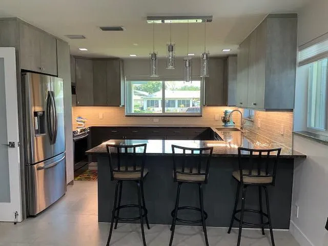 a kitchen with stainless steel appliances granite countertop a table chairs in it and wooden floors