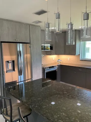 a kitchen with stainless steel appliances kitchen island granite countertop a refrigerator and a stove top oven