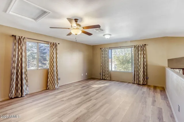 a view of an empty room with a window and wooden floor
