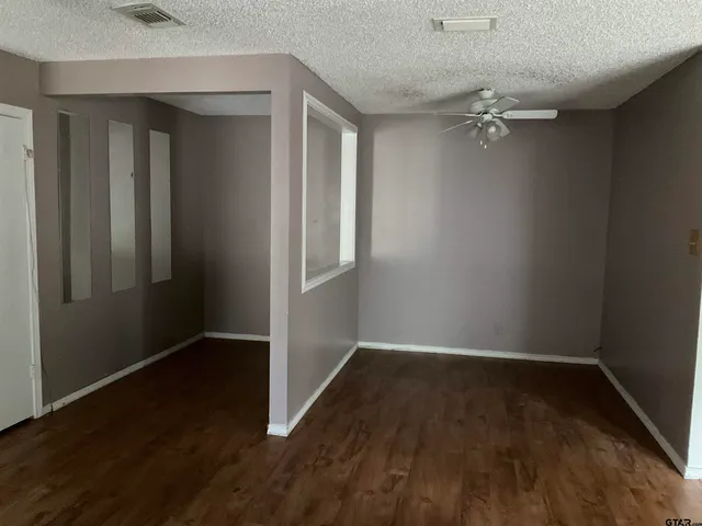 an empty room with wooden floor closet and windows