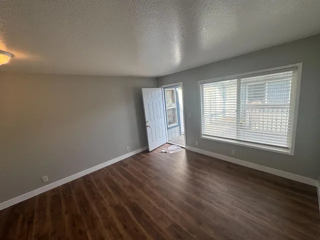 a view of an empty room with wooden floor and a window