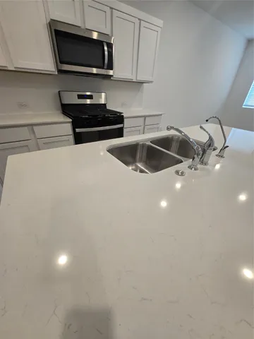 a kitchen with stainless steel appliances a stove a sink and a microwave