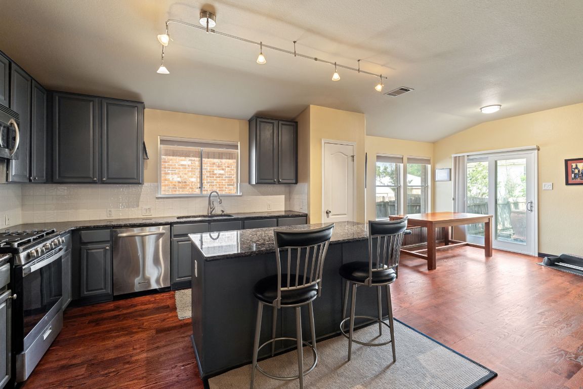 2114 Desco Drive Austin, TX 78748 - Photo 2 of 40 Kitchen featuring stainless steel appliances, lofted ceiling, a sink, tasteful backsplash, and a kitchen island