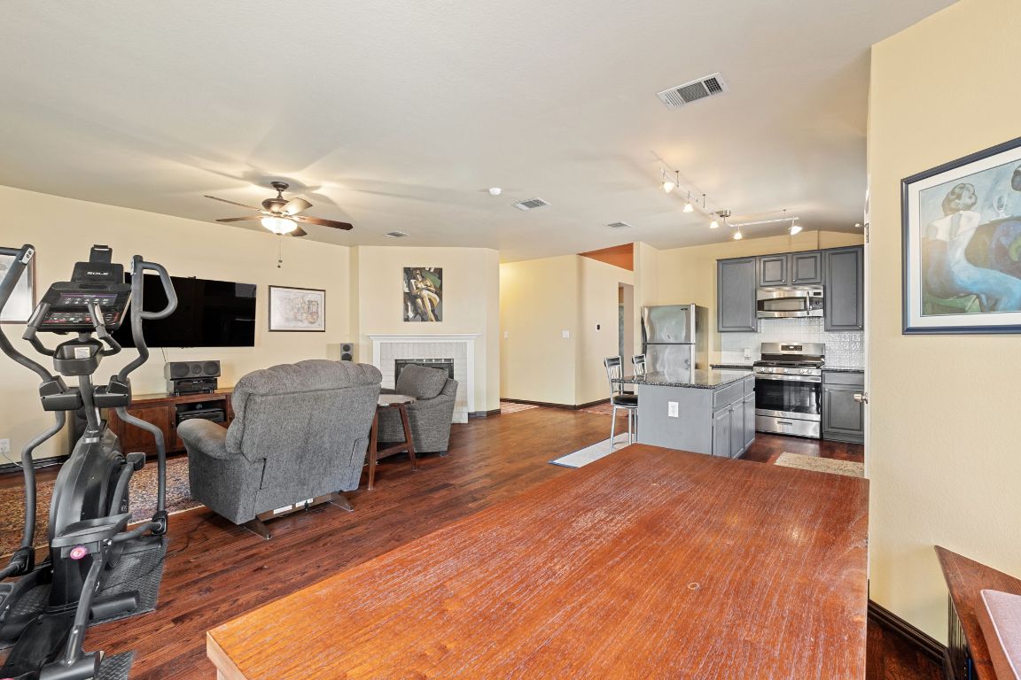 2114 Desco Drive Austin, TX 78748 - Photo 25 of 40 Living area featuring dark wood-type flooring, a ceiling fan, a brick fireplace, and baseboards