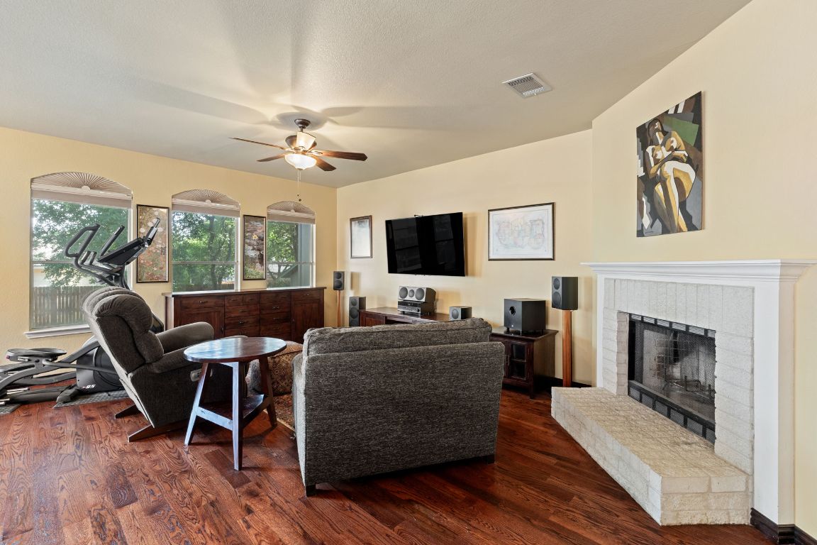 2114 Desco Drive Austin, TX 78748 - Photo 27 of 40 Living room featuring a ceiling fan, dark wood-style floors, and a fireplace