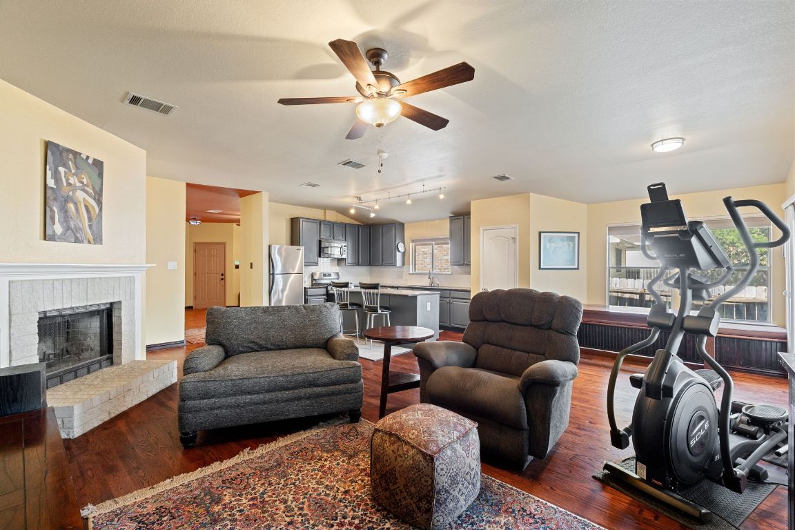2114 Desco Drive Austin, TX 78748 - Photo 29 of 40 Living area with dark wood-style floors, ceiling fan, and a brick fireplace
