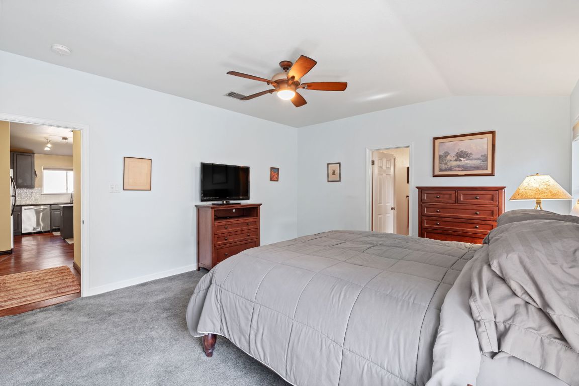 2114 Desco Drive Austin, TX 78748 - Photo 31 of 40 Bedroom with dark colored carpet, freestanding refrigerator, lofted ceiling, ceiling fan, and baseboards