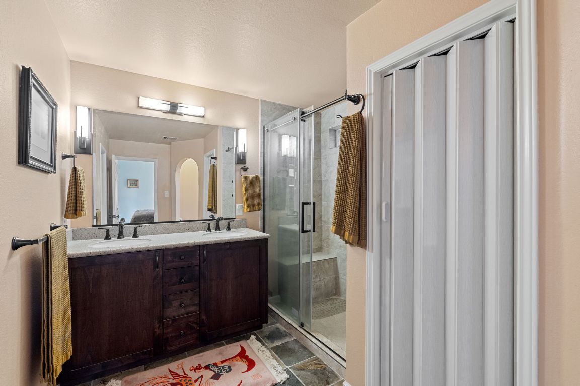 2114 Desco Drive Austin, TX 78748 - Photo 5 of 40 Full bathroom featuring a stall shower, double vanity, and connected bathroom