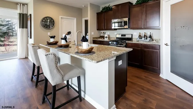 a kitchen with stainless steel appliances granite countertop a table chairs in it and wooden floors