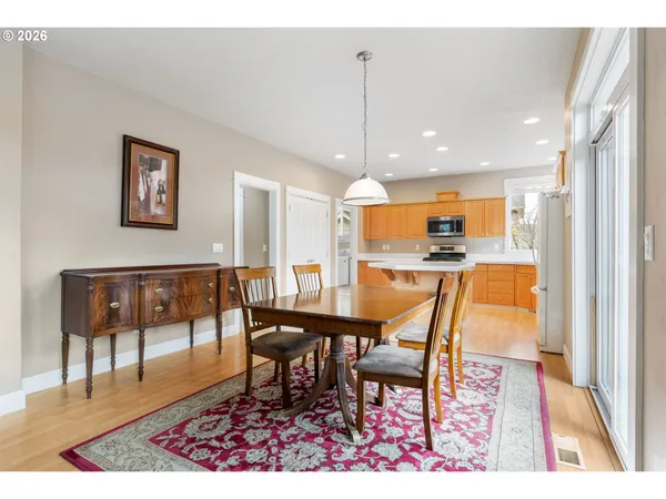 a view of a dining room and livingroom with furniture wooden floor a rug a painting and a chandelier