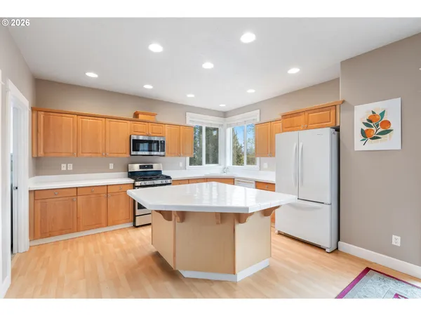 a kitchen with stainless steel appliances granite countertop a refrigerator a sink dishwasher and a stove with wooden floor