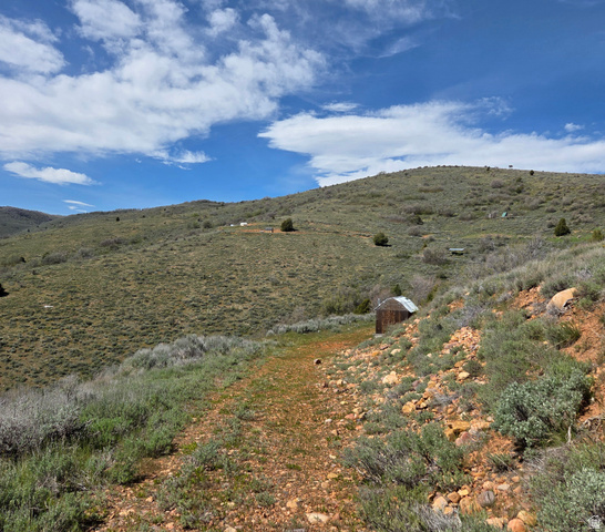 3325 North Oak Cyn Road, Unit 490 Huntsville, UT 84317 - Photo 2 of 25 Expansive rural landscape featuring a single-track path, varied low-lying vegetation, distant hills, and a small rustic structure