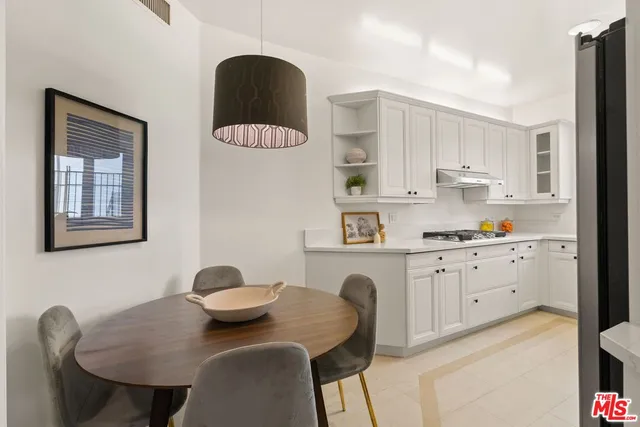 a kitchen with stainless steel appliances granite countertop a table chairs stove and white cabinets