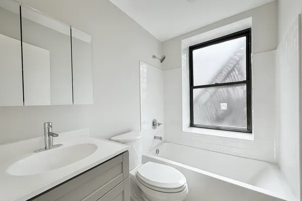 a bathroom with a toilet a sink a mirror a window and vanity