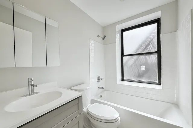 a bathroom with a toilet a sink a mirror a window and vanity