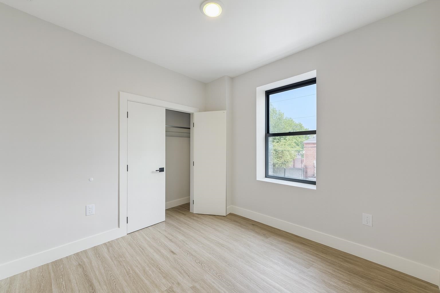 103 Bostwick Avenue, Unit 3A Jersey City, NJ 07305 - Photo 4 of 18 an empty room with wooden floor and windows