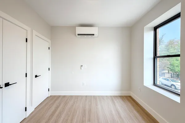 a view of an empty room with wooden floor and a window