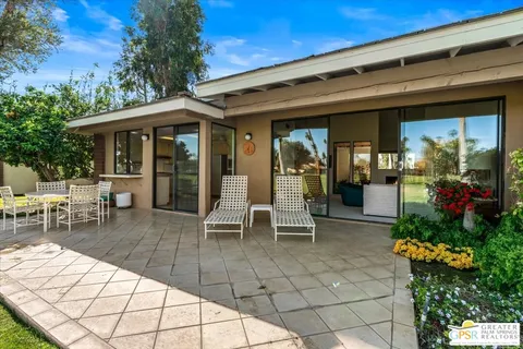 a view of a patio with table and chairs potted plants and floor to ceiling window