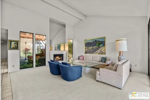 a living room with furniture kitchen view and a large window