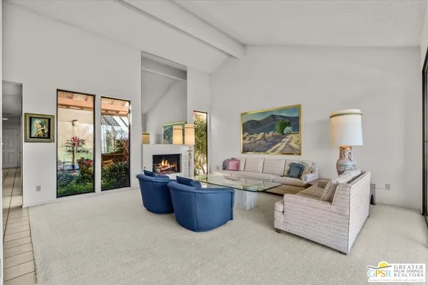 a living room with furniture kitchen view and a large window