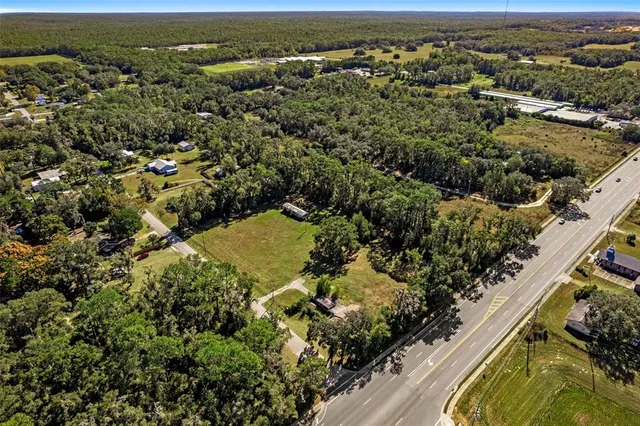 an aerial view of residential houses with outdoor space and trees