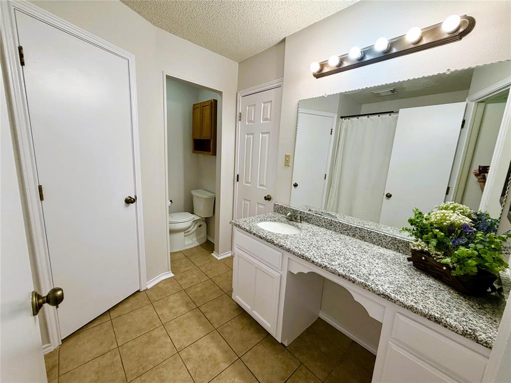 6612 Patsy Lane Watauga, TX 76148 - Photo 27 of 32 Bathroom vanity featuring a granite-style countertop with an integrated sink, white cabinetry, a large wall-mounted mirror, and tile flooring