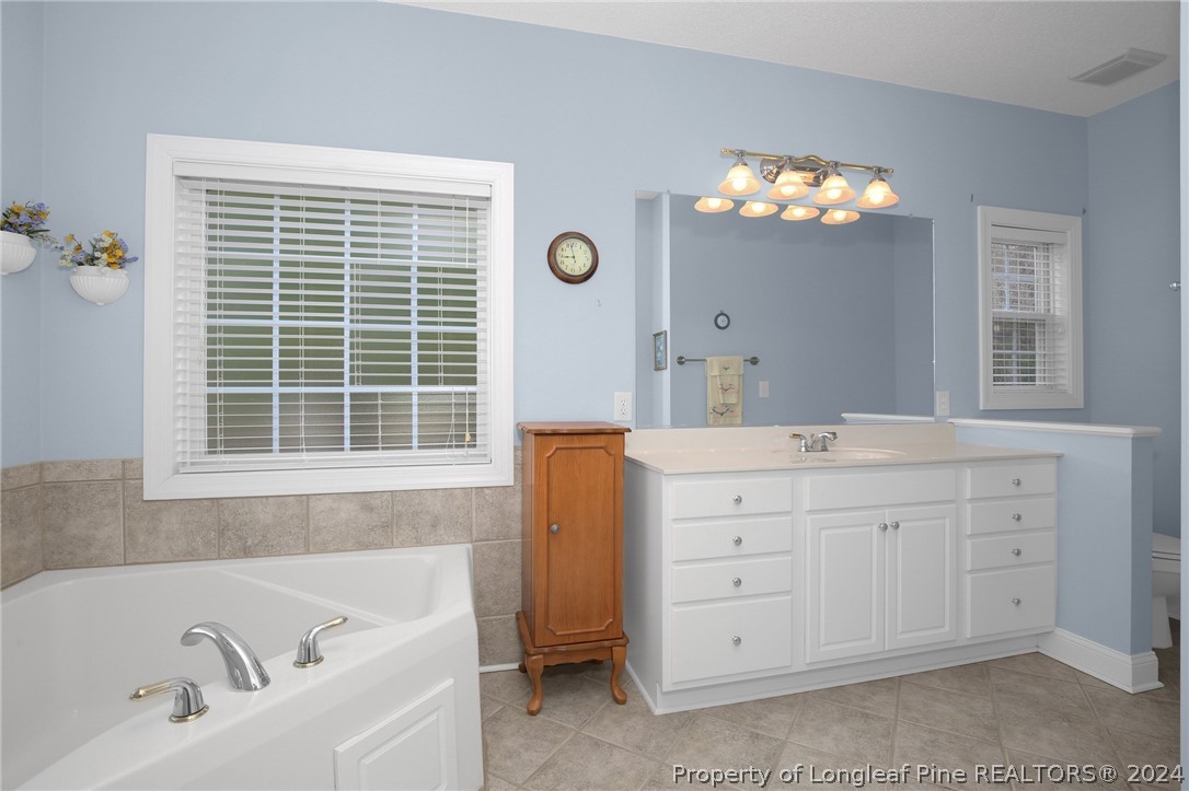 10703 Aberdeen Road Aberdeen, NC 28315 - Photo 19 of 33 a bathroom with a tub sink double vanity and a window
