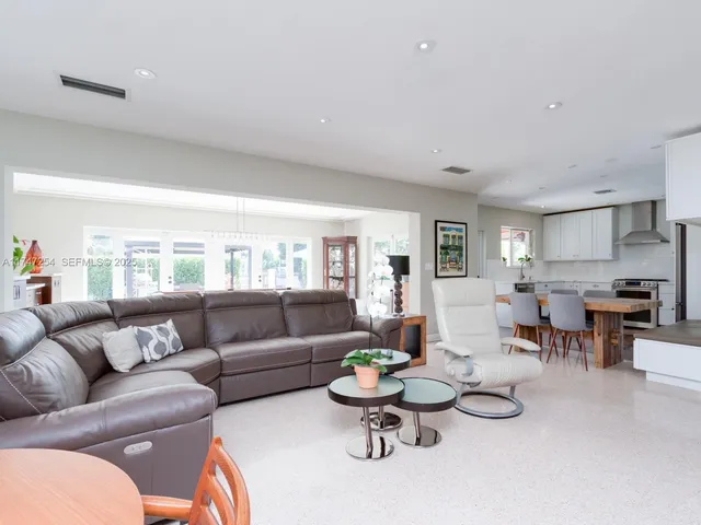 a living room with furniture and a dining table with wooden floor