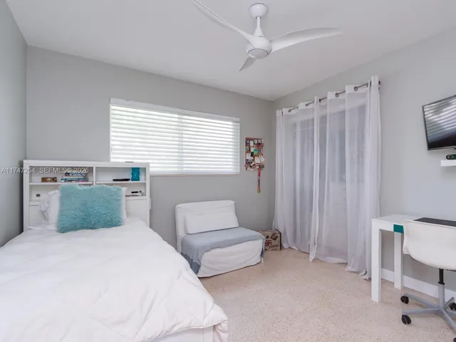 a bedroom with a bed a couch and a flat tv screen on the dresser