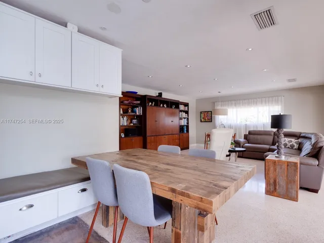 a dining hall with stainless steel appliances kitchen island granite countertop a table chairs and a refrigerator