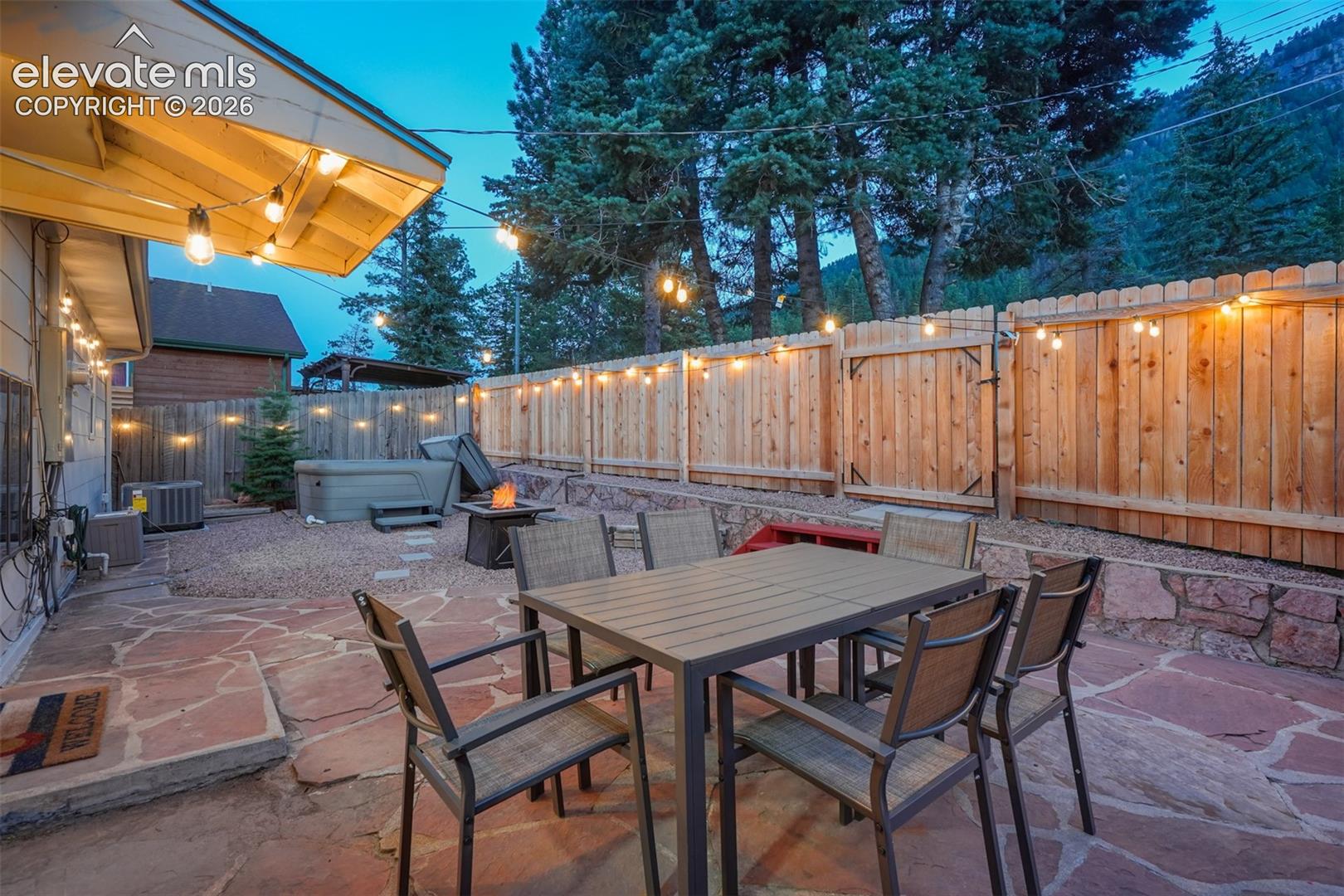 9955 Mesa Road Cascade, CO 80809 - Photo 5 of 41 Flagstone patio, privacy fencing, gravel landscaping, built-in hot tub, and a fire pit