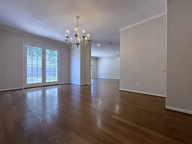 a view of empty room with wooden floor and chandelier